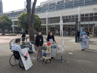 JR桜木町駅前広場にて募金の呼びかけやパネルによる限定募金グッズのPRしている写真